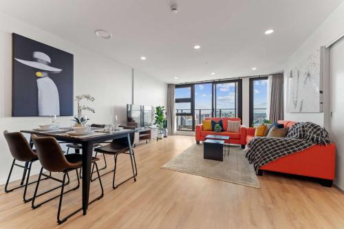 a living room with a table and a red couch at Modern Penthouse 3 Bed & 2 Bath-Skytower View-Pool in Auckland