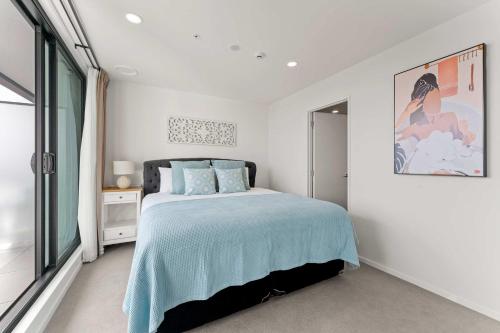 a white bedroom with a bed and a window at Modern Penthouse 3 Bed & 2 Bath-Skytower View-Pool in Auckland