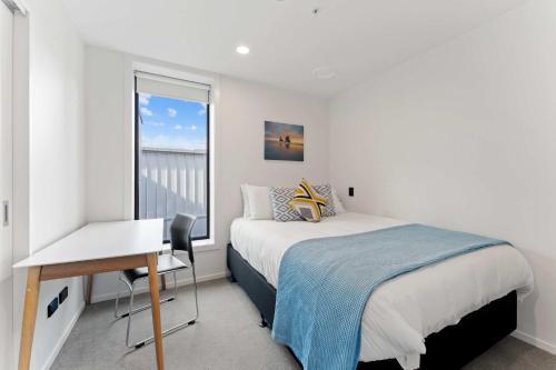 a bedroom with a bed and a desk and a window at Modern Penthouse 3 Bed & 2 Bath-Skytower View-Pool in Auckland