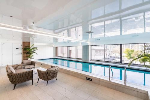 a large swimming pool with two chairs and a table at Modern Penthouse 3 Bed & 2 Bath-Skytower View-Pool in Auckland