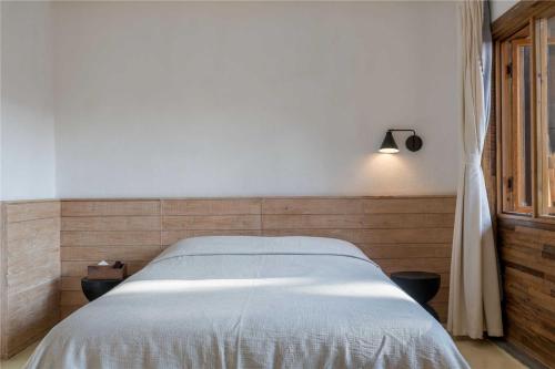 a bedroom with a large bed with a light on it at Shaxi Ancient Town Shiran Mountain Homestay in Jianchuan