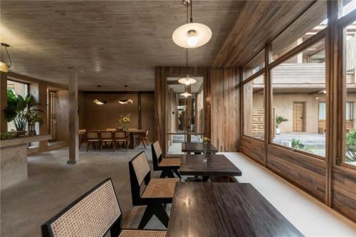 a dining room with wooden tables and chairs at Shaxi Ancient Town Shiran Mountain Homestay in Jianchuan