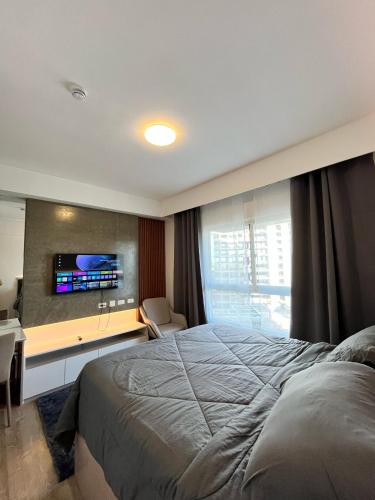 a bedroom with a bed and a tv on a wall at Sleek Stay in Bacolod in Bacolod