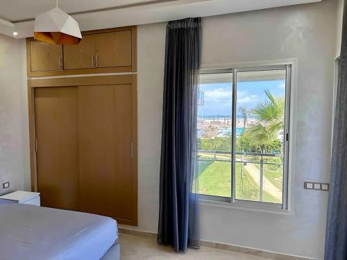 a bedroom with a bed and a large window at Cosy Apartment with sea view in Sidi Rahal