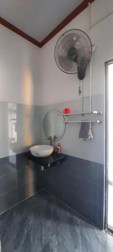 a bathroom with a sink and a fan on the wall at HomeStay Nhà E Phú Yên in Kon Rung (1)