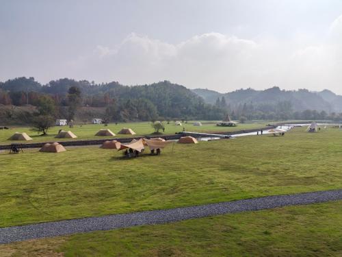 a group of tents in a field next to a river at Anji Bamboo Homestay in Tangkou