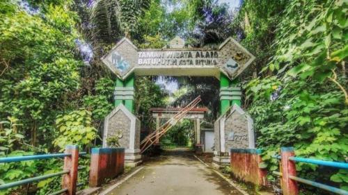 a gate in a forest with a sign on it at Tangkoko Macaca in Rinondoran