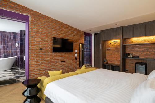 a bedroom with a white bed and a brick wall at Santisookmidtown Pattani in Kampong Rusamileh