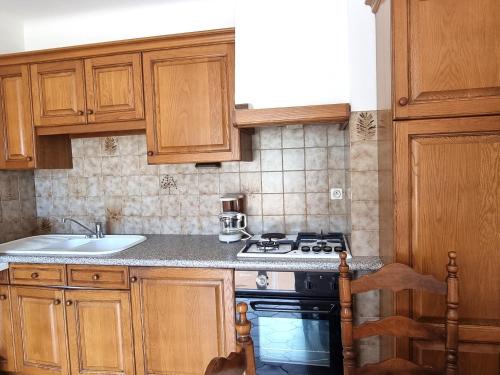 - une cuisine avec des placards en bois, une cuisinière et un évier dans l'établissement Port-Vendres : T2 calme avec parking, grande terrasse ensoleillée et proche du port - FR-1-309-215, à Port-Vendres
