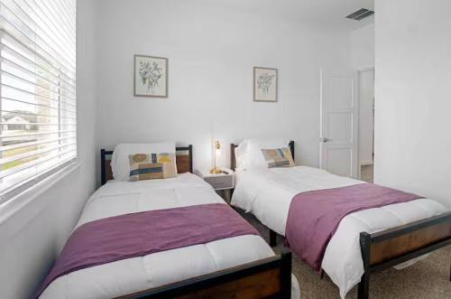 two beds in a room with white walls and a window at Sierra vacation house 1 in Katy