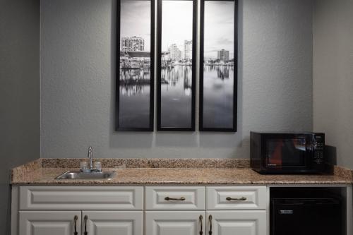 a kitchen with three pictures on the wall above a sink at La Quinta by Wyndham St. Petersburg Northeast *Newly Renovated in St. Petersburg