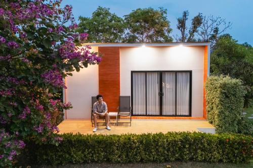 a man sitting on the front porch of a house at Rakmak Kan Resort & Cafe in Ban Wang Dong