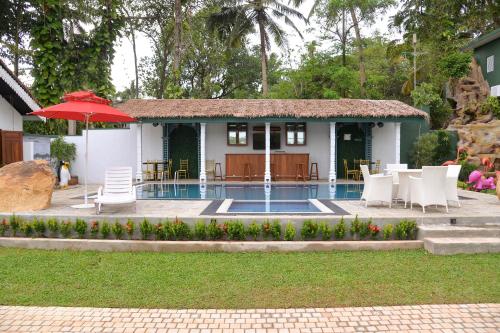 a house with a pool and chairs and an umbrella at The Jungle Dream World in Wadduwa