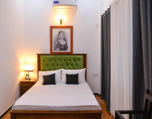 a bedroom with a bed with a green headboard at The Jungle Dream World in Wadduwa