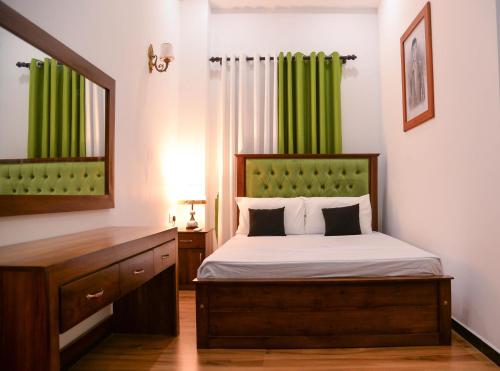 a bedroom with a bed with a mirror and green curtains at The Jungle Dream World in Wadduwa