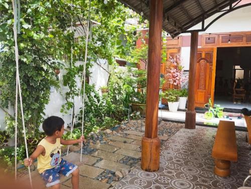 a young boy sitting on a swing in a garden at Gia Nguyễn Homestay Bình Thuận in Tuy Phong