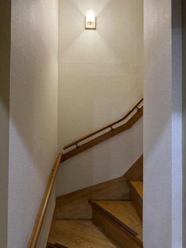 a stairway with a light on the wall and a stair case at Nichika House にちか民泊 in Funabashi