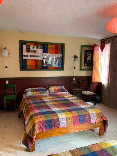 a bedroom with a bed with a colorful blanket at Flying Donkey in Otavalo
