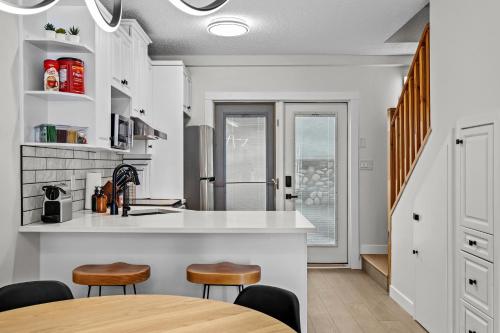 a kitchen with white counters and stools and a table at 2BR 2BA Harvie Heights Townhouse retreat with views in Canmore
