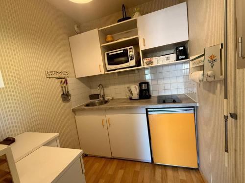 Elle comprend une petite cuisine avec des placards blancs et un réfrigérateur jaune. dans l'établissement Arcachon: Appartement proche plages avec balcon et parking - FR-1-433-136, à Arcachon