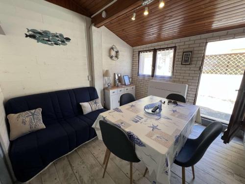 un salon avec une table et un canapé bleu dans l'établissement Maison confortable proche centre, climatisée, 4 personnes - FR-1-701-88, à Valras-Plage