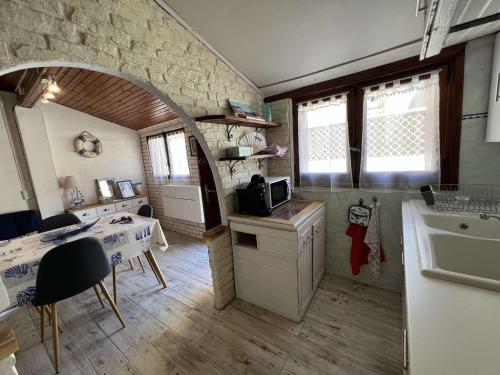 une cuisine avec un évier, une table et un porte-parole dans l'établissement Maison confortable proche centre, climatisée, 4 personnes - FR-1-701-88, à Valras-Plage