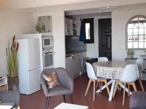 une cuisine avec une table et des chaises et un réfrigérateur blanc dans l'établissement Villa T3 avec climatisation près du lac à Le Barcarès - FR-1-782-75, au Barcarès