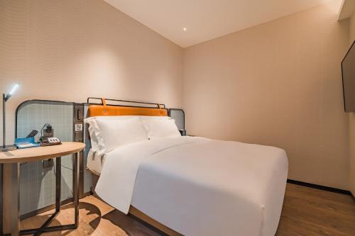 a bedroom with a large white bed and a table at Echarm International Hotel Guangzhou South Railway Station Zhongcun Metro Station Branch - Free Shuttle Bus to Canton Fair Complex During Canton Fair Period & Free Deliver Service to Guangzhou Baiyun International Airport in Guangzhou