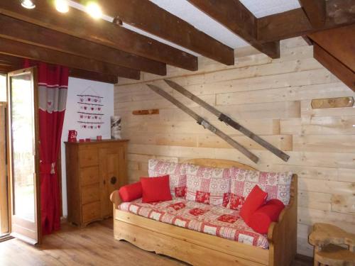 - une chambre avec des murs en bois et un lit avec des oreillers rouges dans l'établissement Chalet confortable 45 m², 5 couchages avec jardin à Barcelonnette - FR-1-804-54, à Barcelonnette