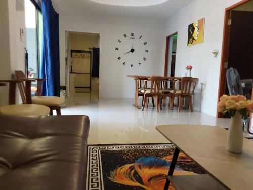 a living room with a table and a clock on the wall at Suksabai Raiwan and Pool Villa in Jomtien Beach