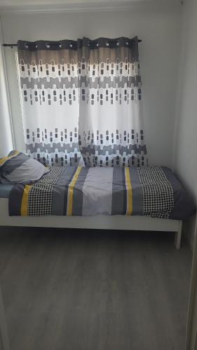 a bed in a room with a window with a curtain at Une Maison chaleureuse in Lebbeke
