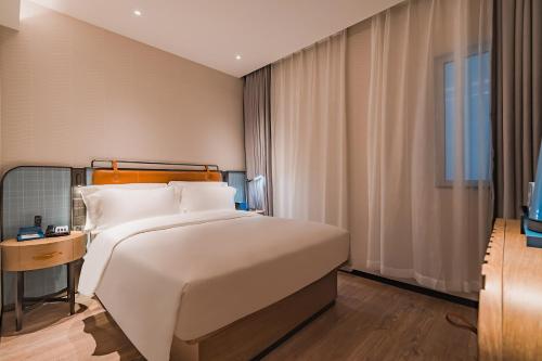 a bedroom with a large white bed and a window at Echarm International Hotel Guangzhou South Railway Station Zhongcun Metro Station Branch - Free Shuttle Bus to Canton Fair Complex During Canton Fair Period & Free Deliver Service to Guangzhou Baiyun International Airport in Guangzhou