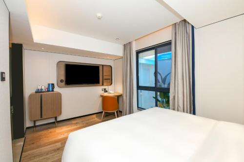 a hotel room with a bed and a television at Echarm International Hotel Guangzhou South Railway Station Zhongcun Metro Station Branch - Free Shuttle Bus to Canton Fair Complex During Canton Fair Period & Free Deliver Service to Guangzhou Baiyun International Airport in Guangzhou