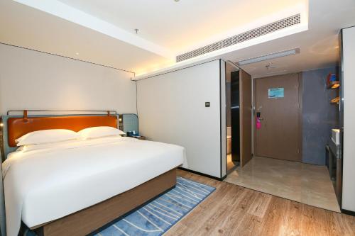 a bedroom with a large white bed and a sliding door at Echarm International Hotel Guangzhou South Railway Station Zhongcun Metro Station Branch - Free Shuttle Bus to Canton Fair Complex During Canton Fair Period & Free Deliver Service to Guangzhou Baiyun International Airport in Guangzhou