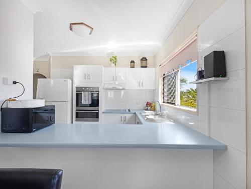 a white kitchen with a large white counter top at Beachside 2-Bed Apt in Hervey Bay with Parking in Torquay