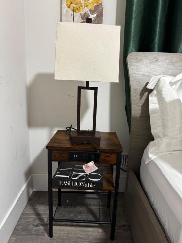 a table with a lamp on it next to a bed at Gateway to Serenity-Welcome home in London