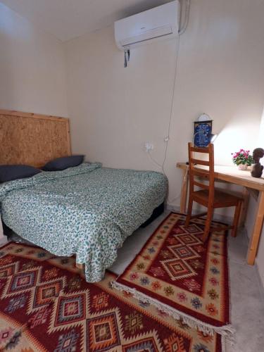 a bedroom with a bed and a table and a chair at guest house אשראם בכרמל - אכסניה in Dāliyat el Karmil
