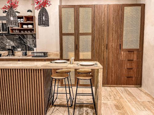 a kitchen with a counter with stools at a bar at Bagá 201 By Rotamundos in Playa del Carmen