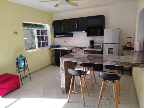 a kitchen with a counter and bar stools in it at Casa chary in Puerto Morelos