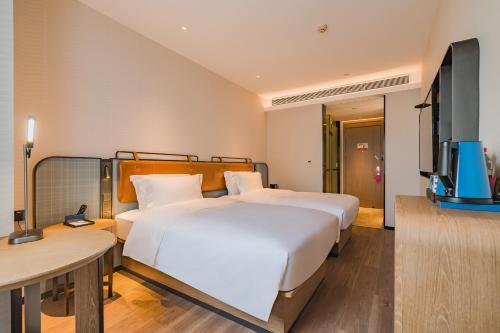 a hotel room with two beds and a television at Echarm International Hotel Guangzhou South Railway Station Zhongcun Metro Station Branch - Free Shuttle Bus to Canton Fair Complex During Canton Fair Period & Free Deliver Service to Guangzhou Baiyun International Airport in Guangzhou