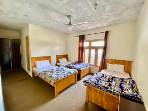 a room with two beds and a window at Vantage Lodge in Skardu