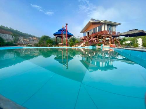 une piscine du complexe avec une maison en arrière-plan dans l'établissement Trang trại Ven Suối 3000m2, Vườn Rau, Hồ Bơi, Thú cưng, à Blach Kon Hin (2)