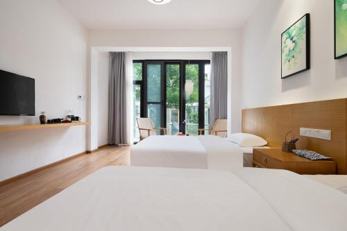 a hotel room with two beds and a tv at 青城山喜遇安下私汤民宿 in Dujiangyan
