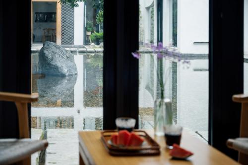a table with a plate of food and a view from a window at 青城山喜遇安下私汤民宿 in Dujiangyan