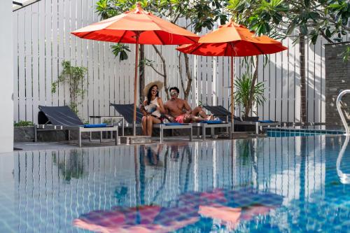two people sitting under umbrellas next to a swimming pool at Citrus Patong Hotel by Compass Hospitality in Patong Beach
