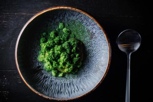 a bowl of broccoli on a table with a spoon at 風の沢 in Kurihara