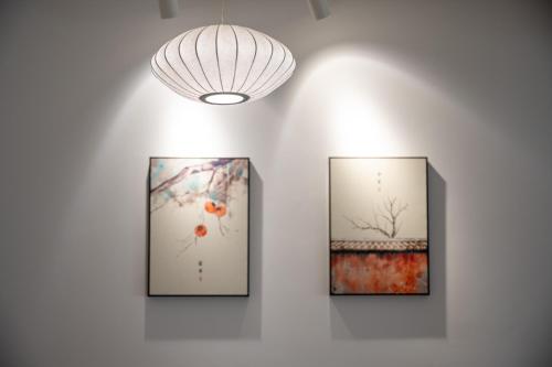 three framed paintings on a wall with a light fixture at 青城山喜遇安下私汤民宿 in Dujiangyan