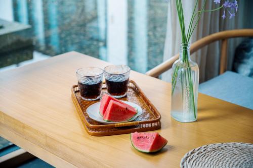 a tray with two glasses of soda and watermelon on a table at 青城山喜遇安下私汤民宿 in Dujiangyan