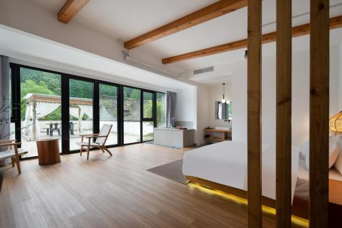 a bedroom with a bed and a table with a chair at 青城山喜遇安下私汤民宿 in Dujiangyan