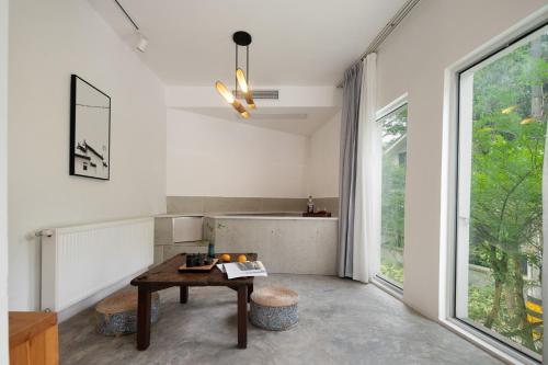 a living room with a table and a large window at 青城山喜遇安下私汤民宿 in Dujiangyan